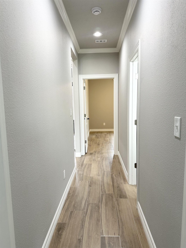 hallway featuring light wood-type flooring and ornamental molding