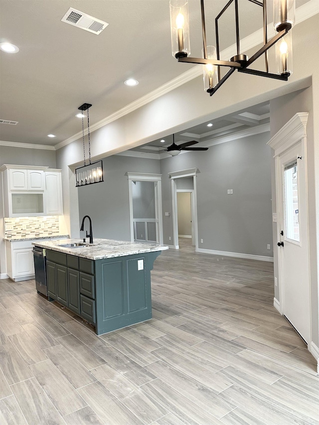 kitchen featuring a center island with sink, ceiling fan with notable chandelier, sink, decorative backsplash, and white cabinetry