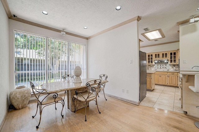 dining room featuring a textured ceiling, crown molding, and light hardwood / wood-style flooring