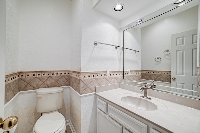 bathroom featuring vanity, tile walls, and toilet