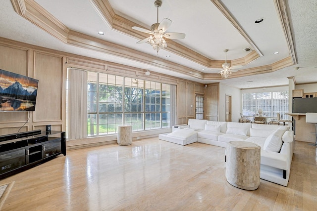 living room with a tray ceiling, ceiling fan, and ornamental molding