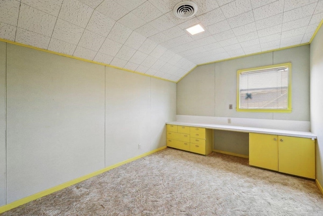 additional living space featuring visible vents, light colored carpet, built in desk, and vaulted ceiling