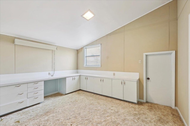 unfurnished office featuring light carpet and vaulted ceiling