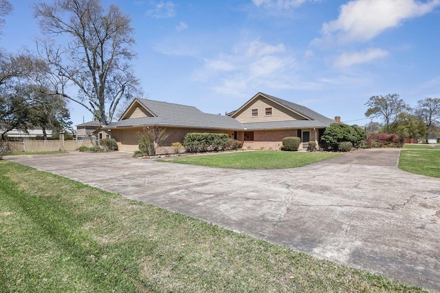 view of front of property featuring brick siding, a front lawn, fence, a garage, and driveway