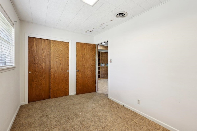 unfurnished bedroom with carpet, visible vents, and baseboards