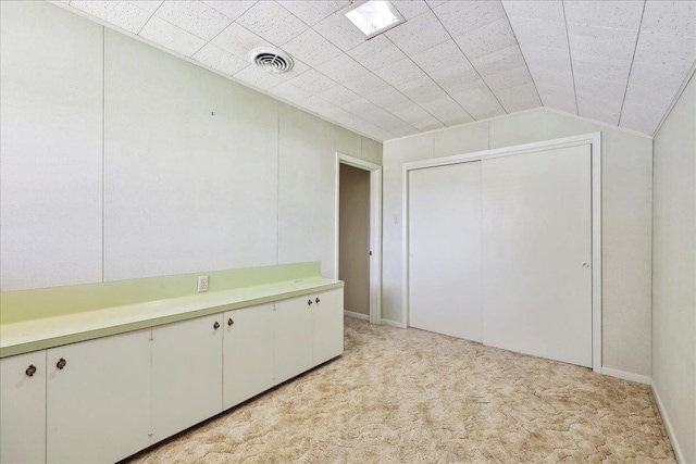 interior space with visible vents, light colored carpet, and vaulted ceiling