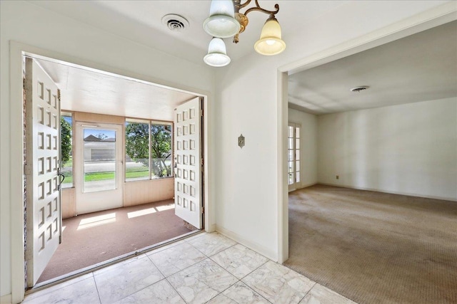 entrance foyer with a wealth of natural light, visible vents, and carpet flooring