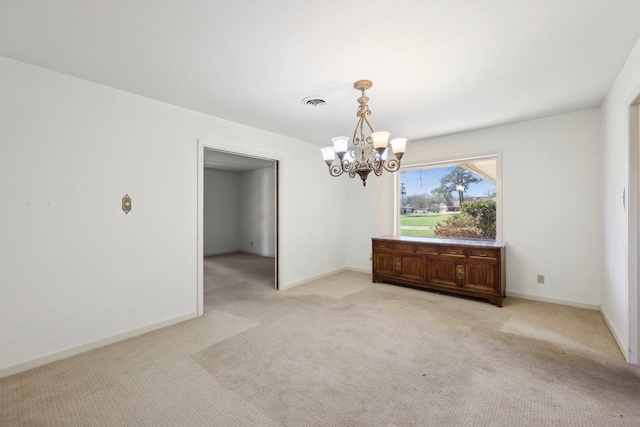 spare room featuring a notable chandelier, light colored carpet, and baseboards