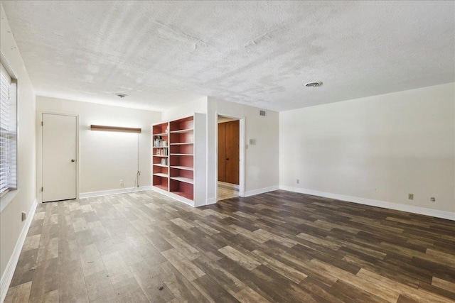 spare room with visible vents, baseboards, a textured ceiling, and wood finished floors