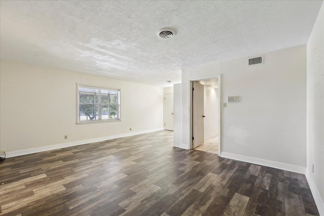 empty room featuring a textured ceiling, wood finished floors, visible vents, and baseboards