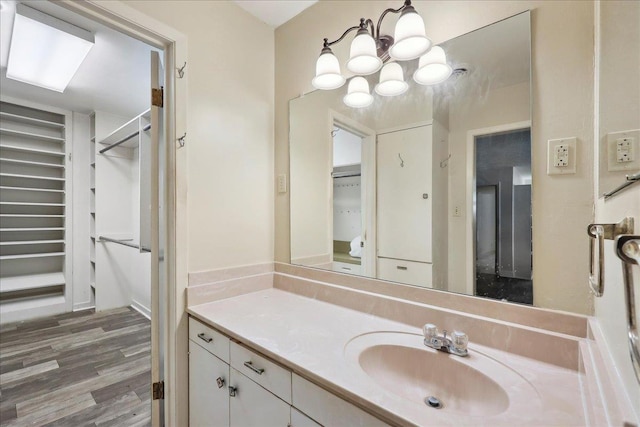 bathroom with vanity, a walk in closet, and wood finished floors