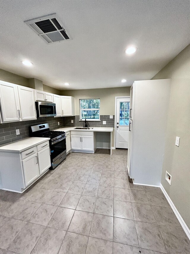 kitchen featuring sink, white cabinets, stainless steel appliances, and light tile patterned floors