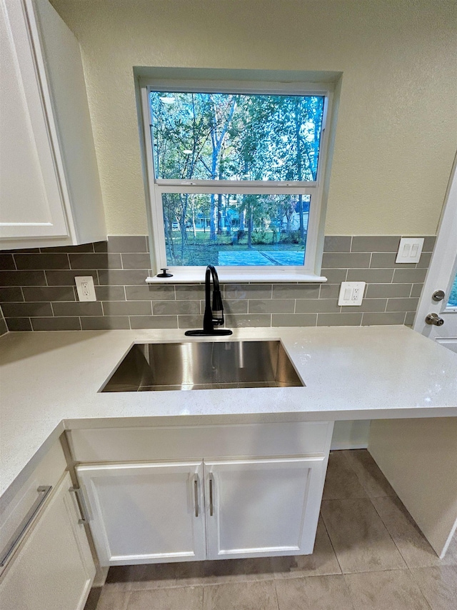 kitchen with backsplash, white cabinetry, sink, and light tile patterned floors