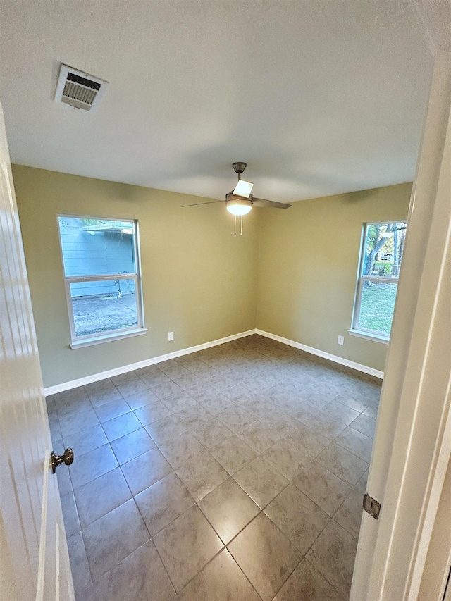 tiled spare room with ceiling fan