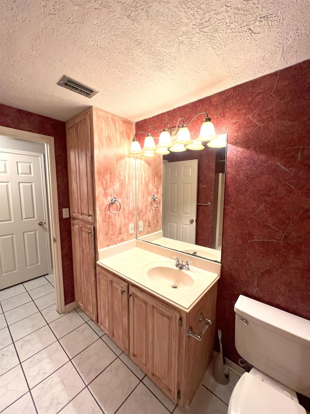 bathroom with tile patterned floors, vanity, a textured ceiling, and toilet