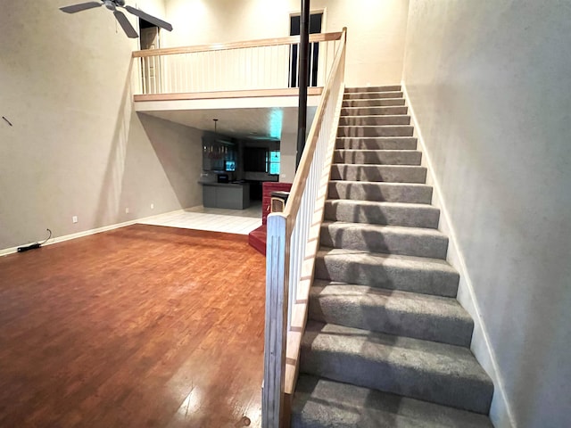 staircase with hardwood / wood-style floors, ceiling fan, and a high ceiling