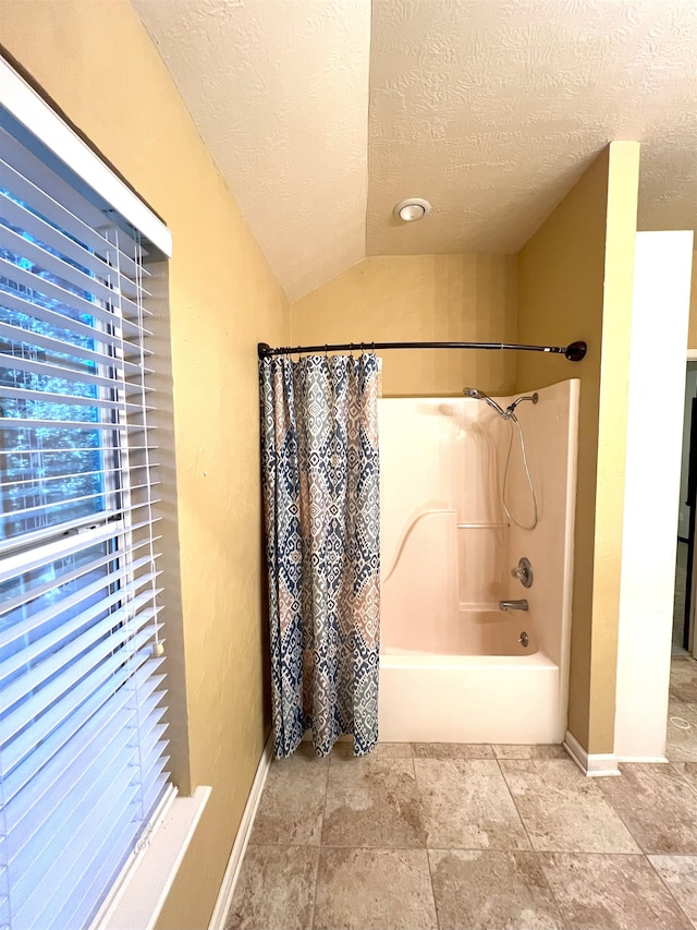 bathroom with shower / bath combo, a textured ceiling, and vaulted ceiling