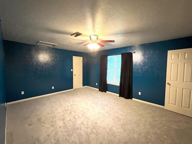 spare room featuring carpet, ceiling fan, and a textured ceiling