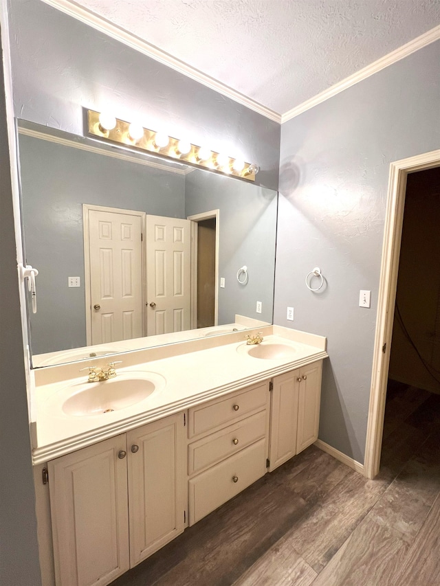 bathroom featuring vanity, wood-type flooring, a textured ceiling, and ornamental molding