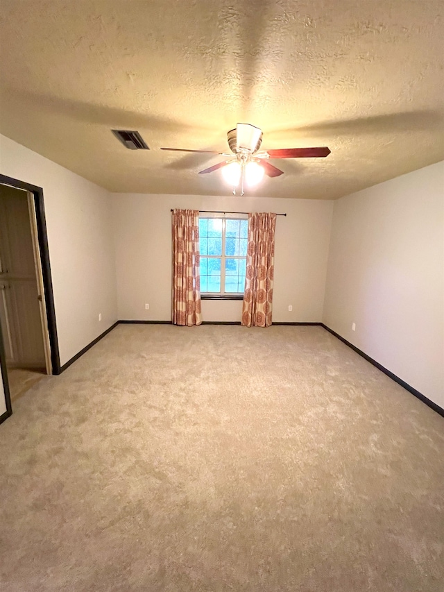 unfurnished room featuring ceiling fan, a textured ceiling, and light carpet