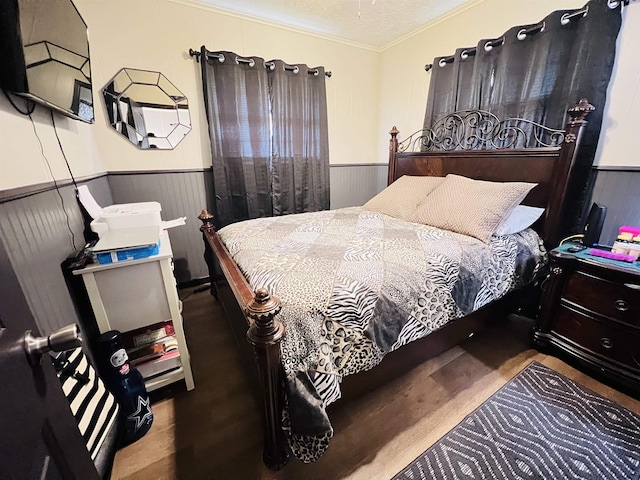 bedroom with a wainscoted wall, ornamental molding, and a textured ceiling