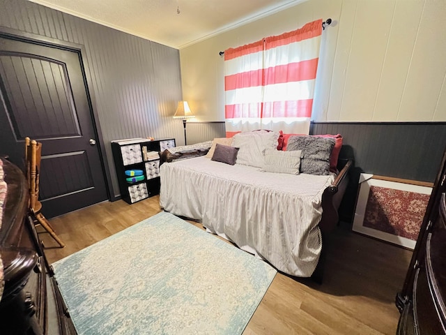 bedroom with wood finished floors and crown molding