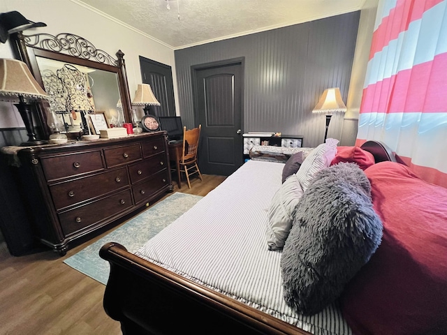 bedroom with crown molding, a textured ceiling, and wood finished floors