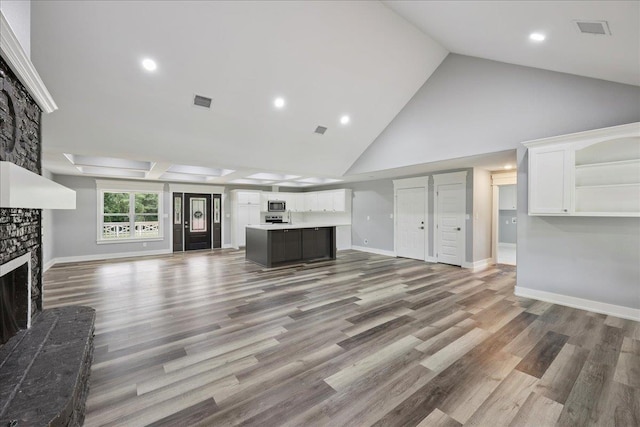 8679 Massey Lake Rd, Silsbee, TX 77656 - unfurnished living room featuring high vaulted ceiling, a stone fireplace, wood finished floors, and recessed lighting