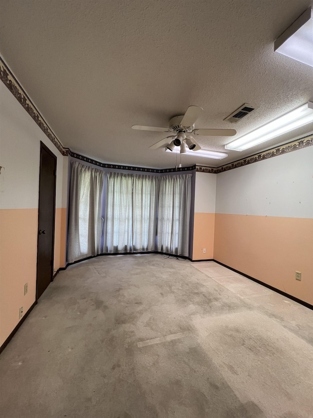 empty room featuring light carpet, ceiling fan, a textured ceiling, and baseboards