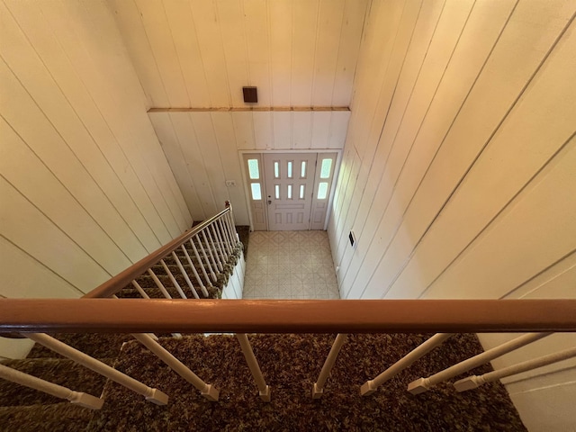 stairway featuring wood walls