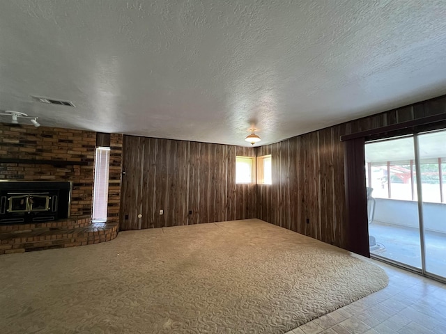 unfurnished living room with a textured ceiling and wood walls