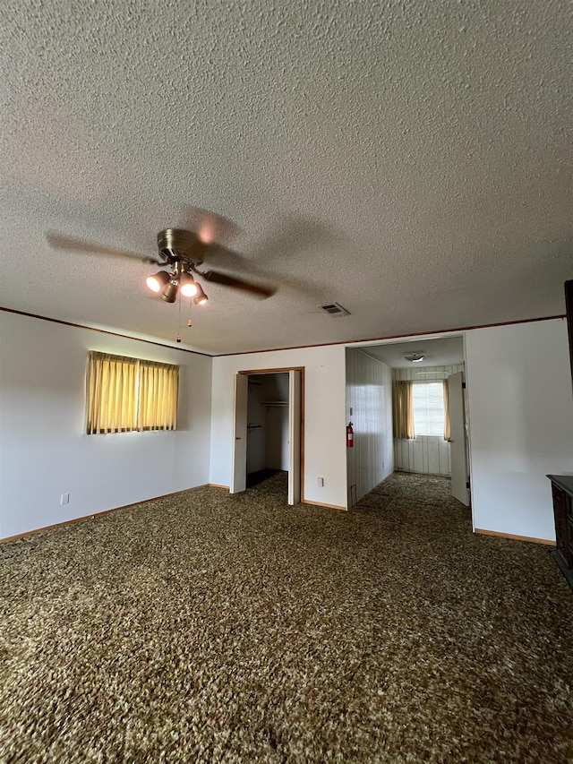carpeted spare room featuring ceiling fan and a textured ceiling