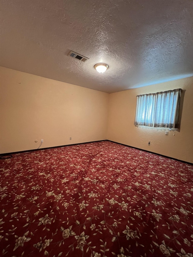 empty room featuring carpet floors, a textured ceiling, and baseboards