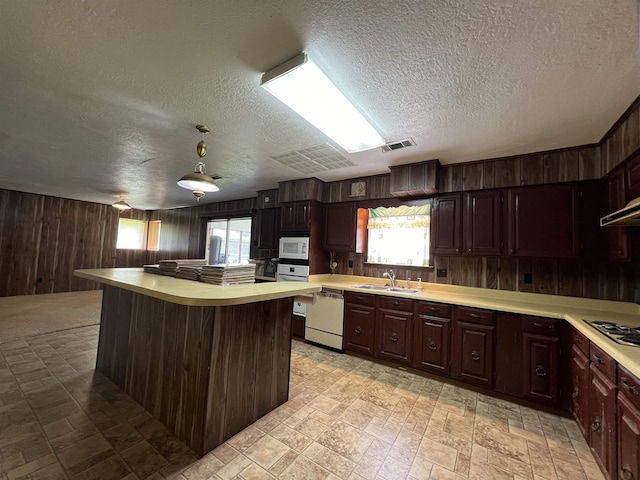 kitchen with white appliances, wood walls, light countertops, a textured ceiling, and plenty of natural light