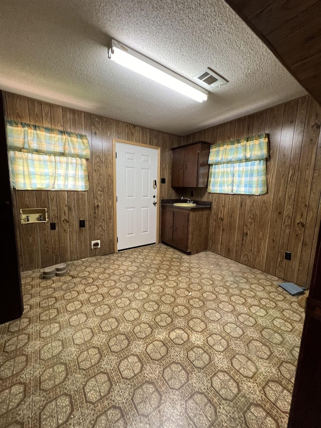 basement featuring wood walls, a textured ceiling, and a sink