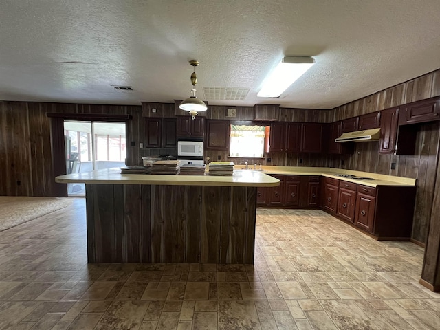 kitchen featuring wooden walls, white appliances, light countertops, light stone finish floors, and range hood