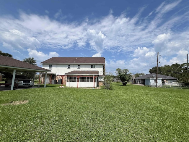 back of house featuring a sunroom, brick siding, and a yard
