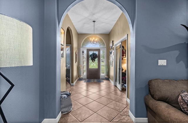 9655 Grapevine Dr, Orange, TX 77630 - tiled foyer featuring arched walkways, baseboards, a chandelier, and a textured wall