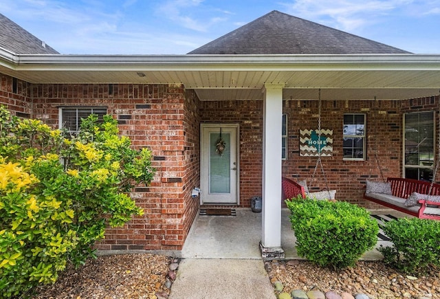9655 Grapevine Dr, Orange, TX 77630 - view of exterior entry featuring brick siding, a shingled roof, and a porch