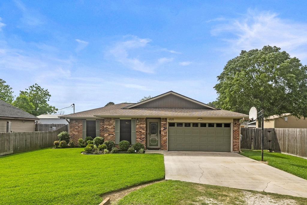 ranch-style house with a garage, fence, driveway, and a front yard