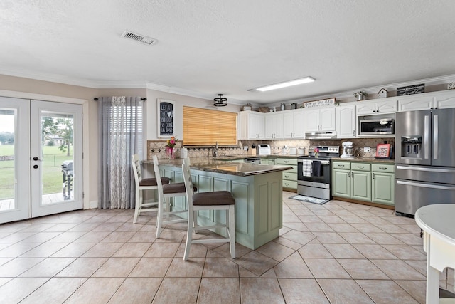 kitchen with a breakfast bar, french doors, white cabinets, appliances with stainless steel finishes, and kitchen peninsula