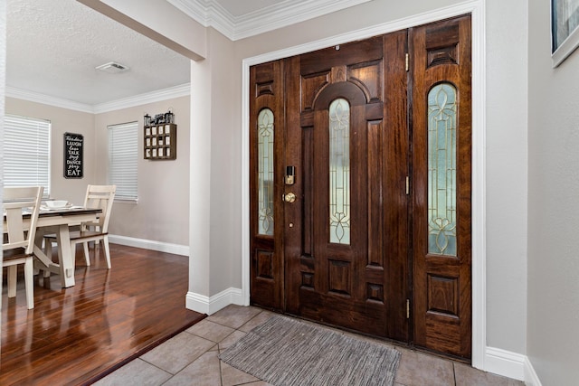 tiled entrance foyer with a textured ceiling and crown molding