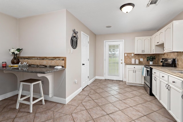 kitchen featuring kitchen peninsula, a kitchen breakfast bar, light tile patterned floors, white cabinets, and stainless steel range with electric cooktop