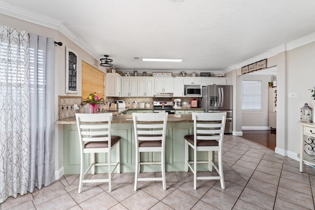 kitchen featuring a kitchen bar, stainless steel appliances, and light tile patterned flooring