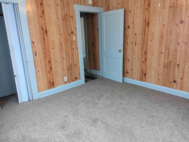 unfurnished room featuring carpet flooring and wooden walls