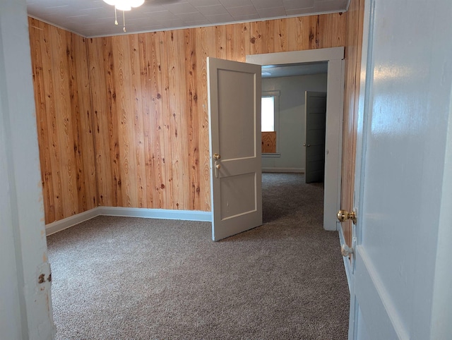 empty room featuring carpet floors and wooden walls