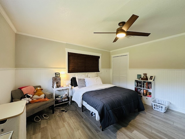 bedroom featuring hardwood / wood-style floors, a closet, ceiling fan, and crown molding