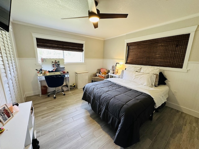 bedroom featuring a textured ceiling, light wood-type flooring, ceiling fan, and crown molding