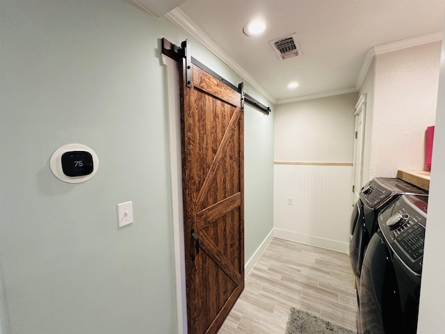 clothes washing area featuring a barn door, washing machine and dryer, and crown molding