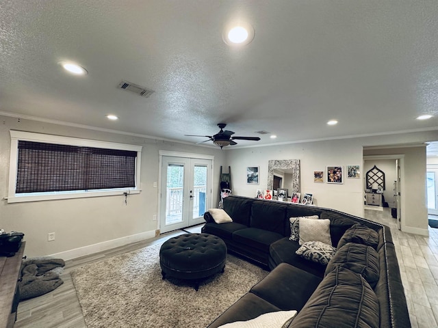 living room featuring crown molding, french doors, a textured ceiling, and light wood-type flooring